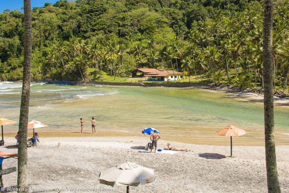 Imagem de uma casa amarela em frente uma piscina natural.